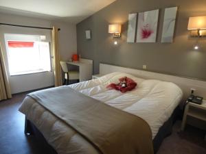 een slaapkamer met een bed met een rode knuffel erop bij Hotel du Centre in Pierrelatte