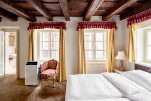 a bedroom with a bed and a chair and windows at Hotel Residence Green Lobster in Prague