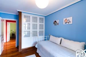 1 dormitorio con paredes azules y 1 cama blanca en Housingleón - Galeria, en León