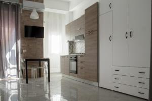 a kitchen with white cabinets and a table and a chair at Una finestra sul glicine in Cirò Marina