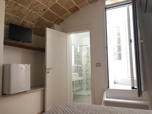 Schlafzimmer mit einem Bett, einem TV und einem Fenster in der Unterkunft Ugento Dimora in Ugento