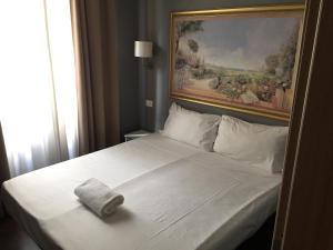 a white bed with a towel on top of it at Rome Travellers Hotel in Rome