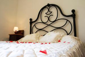 a white bed with red rose petals on it at L'OZioRinco Apartments in Florence