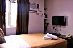 a hotel room with a bed and a tv and towels at The Studio 18 Residences in Manila