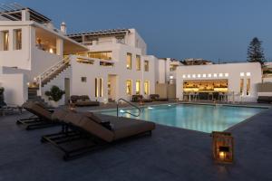 a villa with a swimming pool in front of a house at Rochari Hotel in Mýkonos City