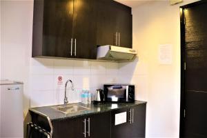 a kitchen with black cabinets and a sink and a microwave at The Studio 18 Residences in Manila