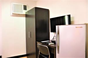a black refrigerator next to a desk with a computer at The Studio 18 Residences in Manila