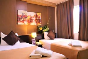 a hotel room with two beds and a painting on the wall at The Studio 18 Residences in Manila