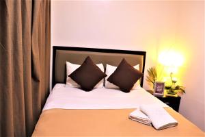 a bed with black and white sheets and pillows at The Studio 18 Residences in Manila