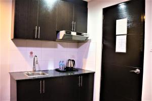 a kitchen with black cabinets and a sink at The Studio 18 Residences in Manila