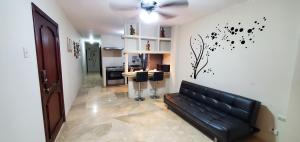 a living room with a black couch and a kitchen at NCG Suite in Guayaquil