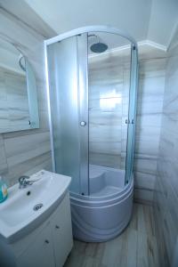 a white bathroom with a shower and a sink at Pensiune Roata Cu Noroc in Sighetu Marmaţiei