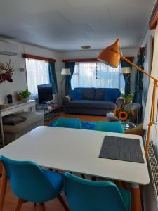 a living room with a white table and blue chairs at kitty"s Chalet Modern en toch knus in Warmond