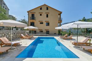 een zwembad met stoelen en parasols naast een gebouw bij Kotor Sunset Apartments in Kotor