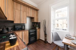 una cucina con armadi in legno e forno a piano cottura nero di City Centre Stylish Apartment at The Meadows Park a Edimburgo