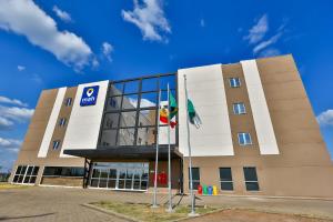 Un edificio con dos banderas delante. en Maringá Airport Hotel, en Maringá