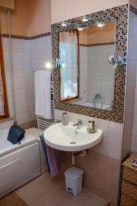 een badkamer met een wastafel, een spiegel en een bad bij A casa di Debby alloggio comodo e accogliente in Foligno