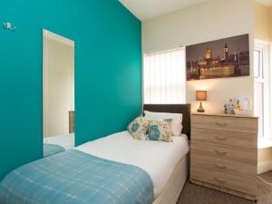 Schlafzimmer mit blauen Wänden, einem Bett und einer Kommode in der Unterkunft Townhouse @ Minshull New Road Crewe in Crewe