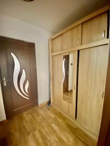 Cette chambre dispose de deux portes en bois et de parquet. dans l'établissement Apartament Sunshine, à Orşova