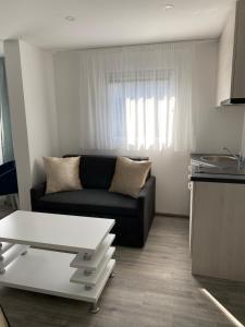 Una sala de estar con un sofá negro y una ventana. en DMApartmani, en Tuzla