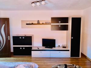 a room with a desk with a television and a shelf at Apartament Sunshine in Orşova