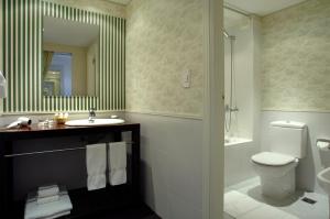 a bathroom with a sink and a toilet and a mirror at Los Acebos Ushuaia Hotel in Ushuaia