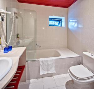 a bathroom with a tub and a toilet and a sink at Aldeia da Fonte Hotel in Lajes do Pico +21 photos