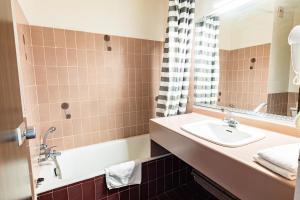 La salle de bains est pourvue d'un lavabo, d'une baignoire et d'un miroir. dans l'établissement Hotel du Port, à Canet