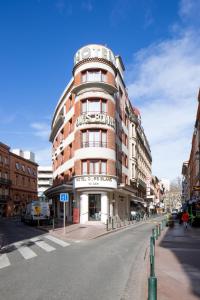 a tall building with a sign on the side of a street at Hotel Ours Blanc - Wilson in Toulouse