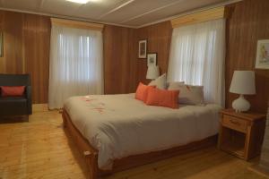 1 dormitorio con 1 cama grande con almohadas de color naranja en Auberge À La Chouenne, en La Malbaie