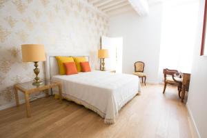 Dormitorio blanco con cama con almohadas de color naranja y amarillo en L'Aubertine en Beaune