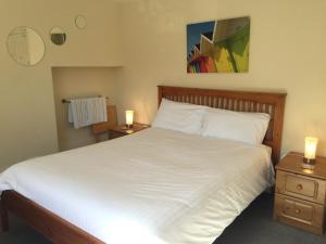 Barbican Reach Guest House في بلايموث: غرفة نوم بسرير ابيض كبير مع مواقف ليلتين