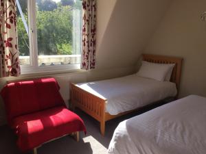 1 dormitorio con 2 camas, silla y ventana en Barbican Reach Guest House, en Plymouth