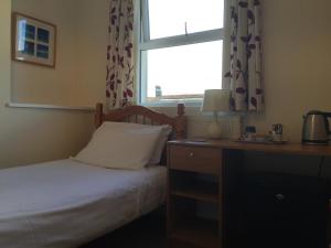 1 dormitorio con cama, ventana y escritorio en Barbican Reach Guest House, en Plymouth