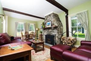 a living room with a couch and a stone fireplace at Bark Eater Inn in Keene