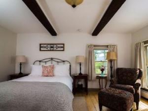 a bedroom with a bed and a chair at Bark Eater Inn in Keene