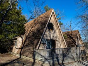 a house with a gambrel roof with a porch at Bar M Resort & Campground in Branson West