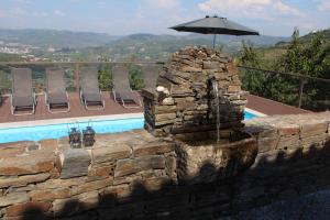 a stone wall with an umbrella next to a swimming pool at Quinta do Pombal Douro in Penajoia