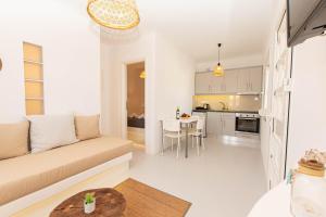 Overview Mykonos Apartments في مدينة ميكونوس: غرفة معيشة ومطبخ مع أريكة وطاولة
