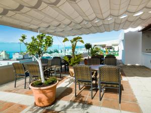 un patio avec des chaises et une table sur le toit dans l'établissement Hotel Monarque El Rodeo, à Marbella