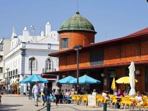 a group of people walking past a building with tables and umbrellas at Beautiful Apartment in Olhão