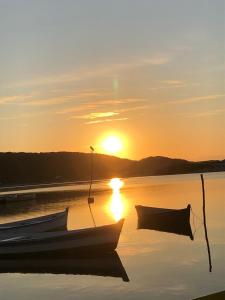 dois barcos sentados na água ao pôr do sol em Pousada Villa Embaú em Guarda do Embaú