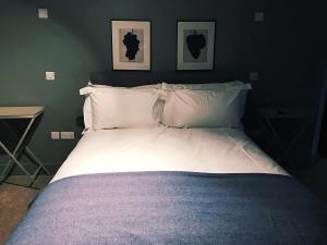 een bed met witte lakens en kussens in een slaapkamer bij The Bell Inn in Lechlade