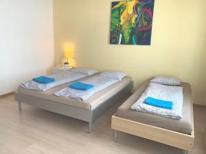 two beds in a room with a painting on the wall at Modtrip Switzerland in Grünenmatt