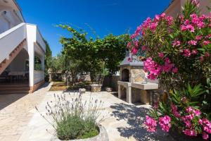 um jardim com flores cor-de-rosa e um banco de pedra em ADRIA-Holiday House with a beautiful pool in Krk em Kornic