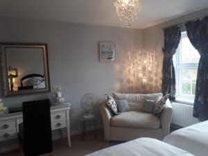 a bedroom with a chair and a mirror and a dresser at Berry House Bed & Breakfast in Littlehampton