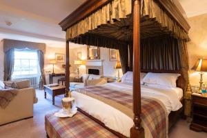 a bedroom with a large canopy bed and a couch at Cavendish Hotel in Baslow