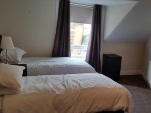 a bedroom with two beds and a window with curtains at The Blackbull Inn Polmont in Polmont