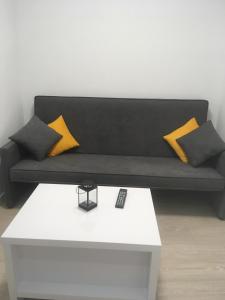 um sofá preto com almofadas amarelas numa mesa branca em APARTAMENTOS A RODA em A Guarda
