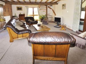 a living room with leather furniture and a couch at Bluebell Farm in Upton upon Severn